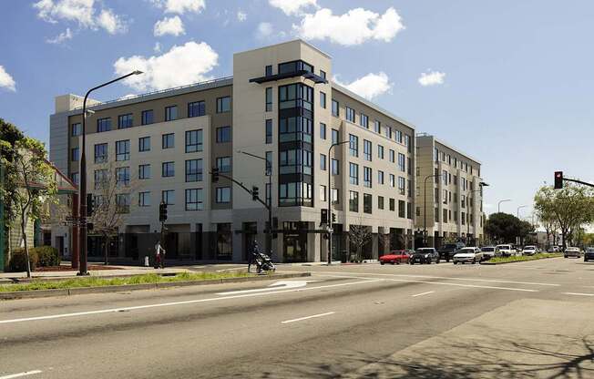 A large building with a grey facade is situated on a street corner.