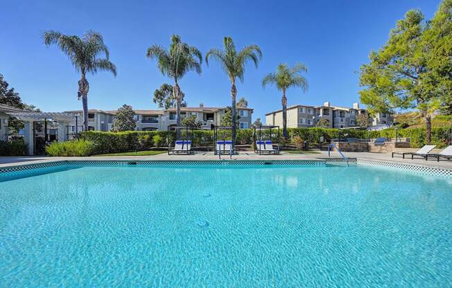 A swimming pool surrounded by palm trees and apartment buildings.