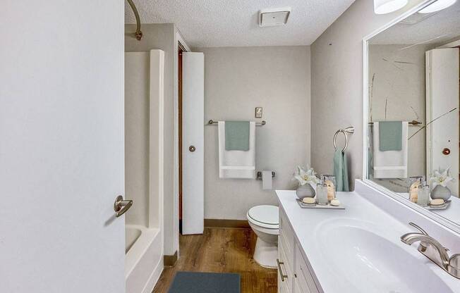 A white bathroom with a toilet, sink, and mirror.