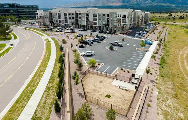 A parking lot in front of a large building with a mountain in the background.