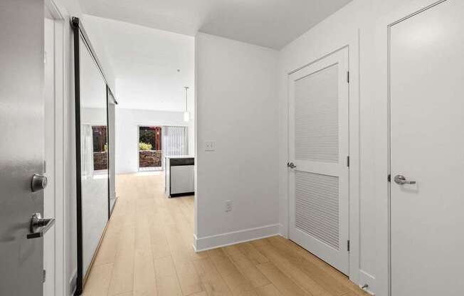 A hallway with white walls and wooden floors.