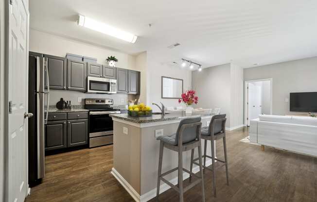 a kitchen with stainless steel appliances and a bar with three stools at MetroPlace at Town Center, Maryland, 20746