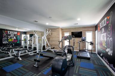 A gym with a variety of equipment including treadmills, weights, and a television.