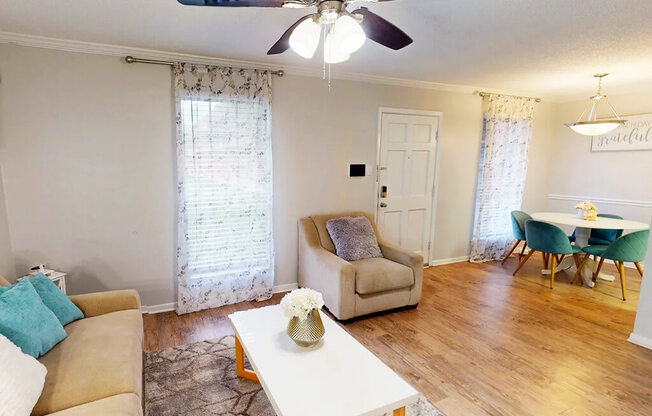 A living room with a beige couch, a white coffee table, and a dining table with chairs.