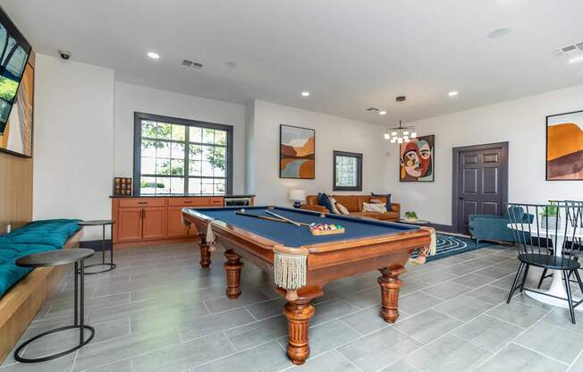 A pool table is in the middle of a room with a blue cushion on it.