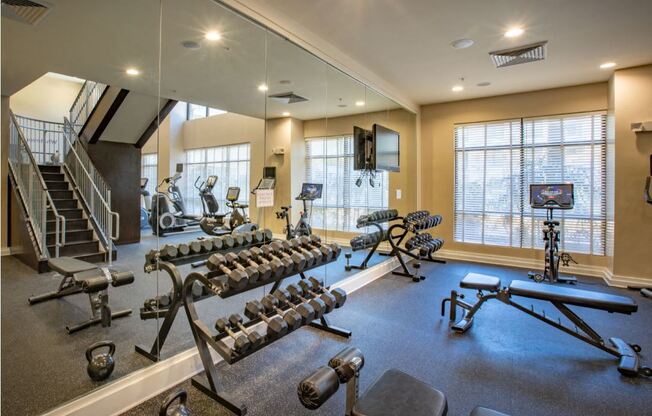 Weight room with benches and peloton bicycle.