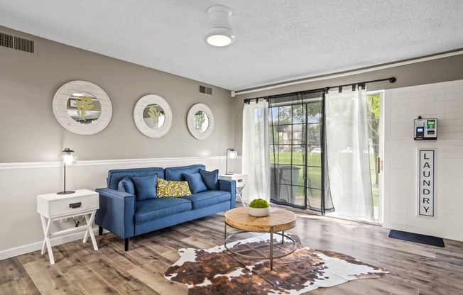 a living room with a blue couch and a coffee table at Beacon Hill and Great Oaks Apartments, Rockford, IL