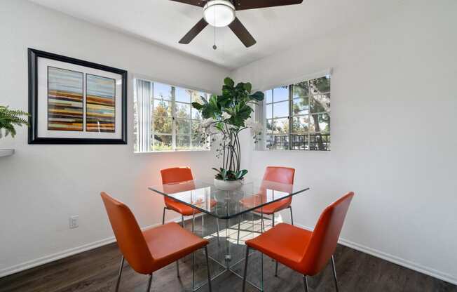 a dining room with a glass table and chairs and a ceiling fan