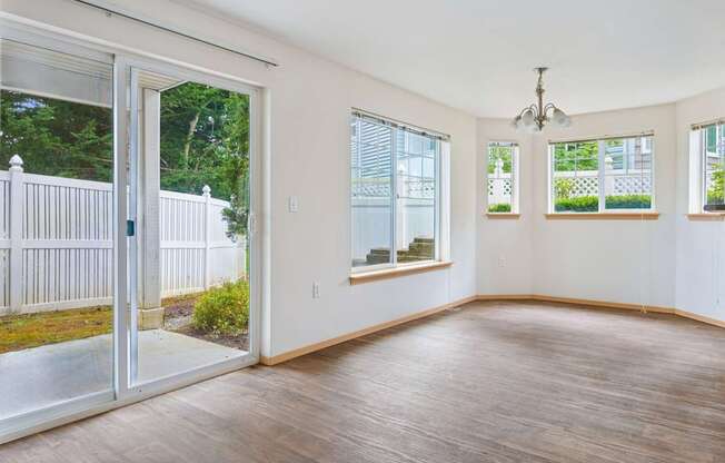 Spacious York dining room with wood floors and glass sliding doors leading to a grassy fenced in patio at Abbey Rowe Apartments in Olympia, WA