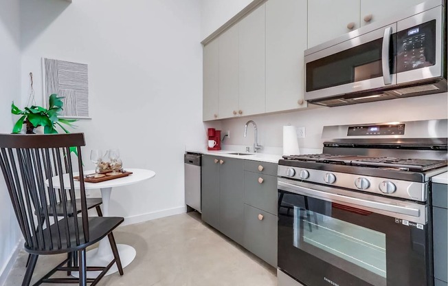 A modern kitchen with a black chair and a white table.