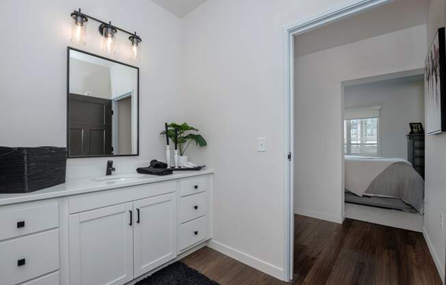 a bathroom with white cabinets and a mirror and a bedroom with a bed at The Crossings at Windsong, Arizona