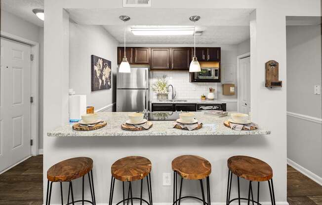 A kitchen with a granite countertop and bar stools.