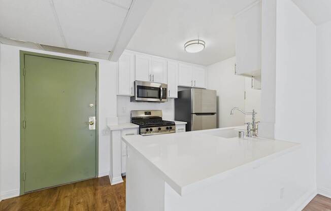 A kitchen with a green door and white countertops.