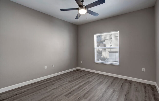 an empty room with a ceiling fan and a window