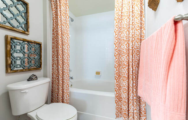 a bathroom with a white toilet next to a bathtub with a orange shower curtain at Heritage Bay, Florida, 34957