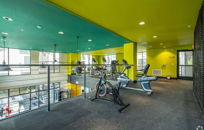 A gym with a yellow wall and a treadmill.