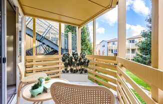 A patio with a chair and a table with a vase on it.