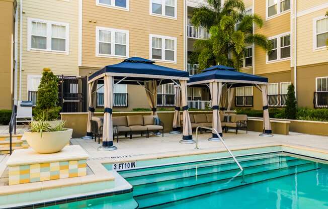 a swimming pool with umbrellas in front of a building