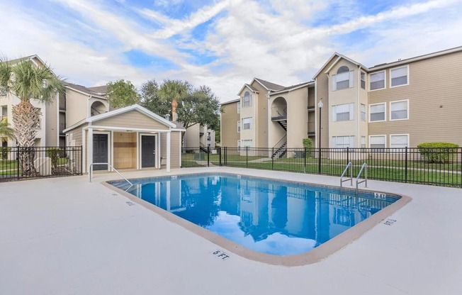 A swimming pool in front of a building with a black fence around it.