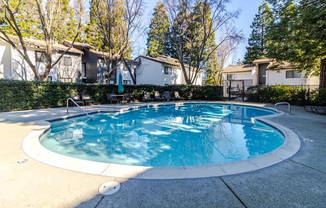 A round above ground pool with a white border and a concrete patio.