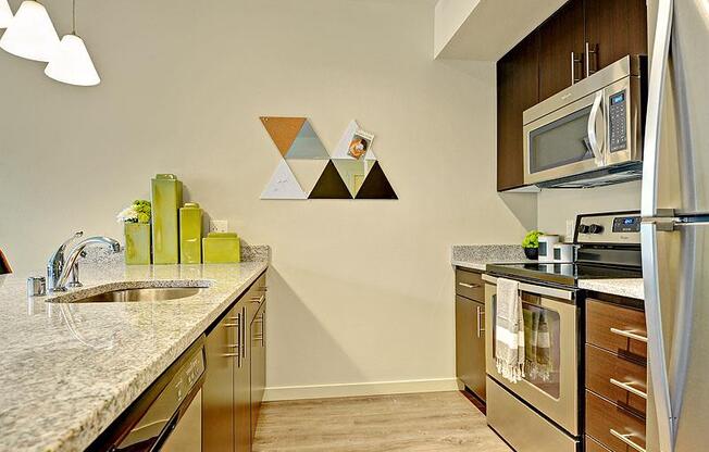 A kitchen with a granite counter top and a white fridge. at Kirkland Crossing Apartments, Kirkland