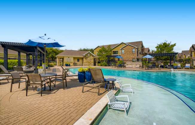 a swimming pool with chairs and umbrellas next to club house