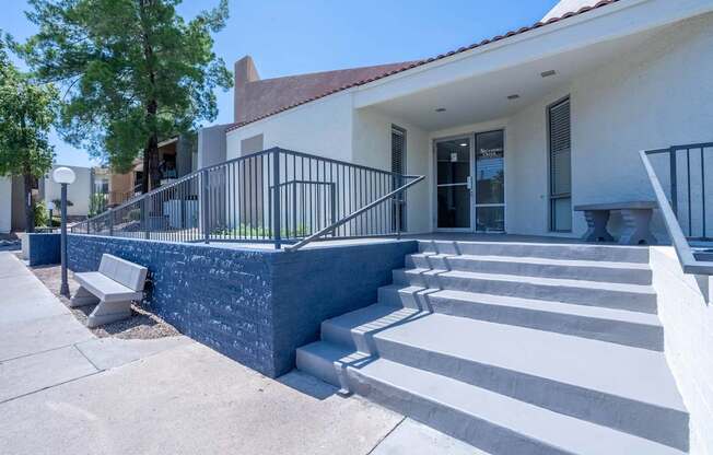 A white house with a black railing and steps leading to the front door.