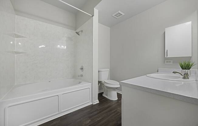 a white bathroom with a tub and a sink and a toilet