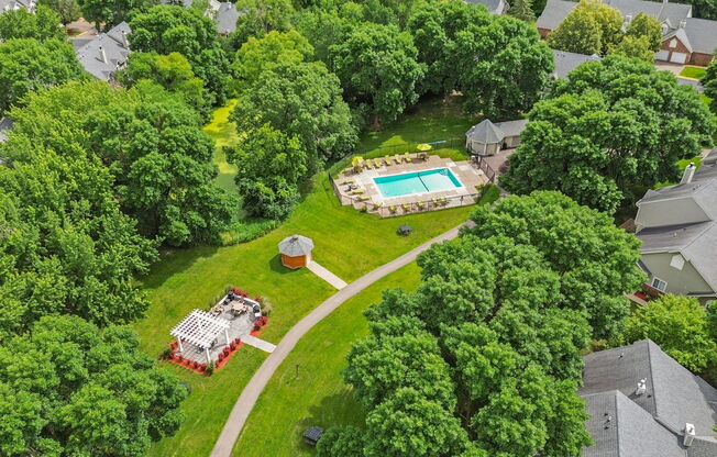 A bird's eye view of a house with a pool surrounded by trees.