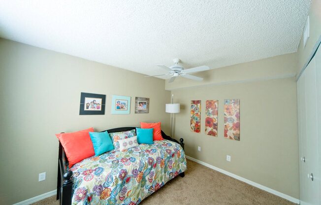 A bedroom with a bed, pillows, and pictures on the wall.