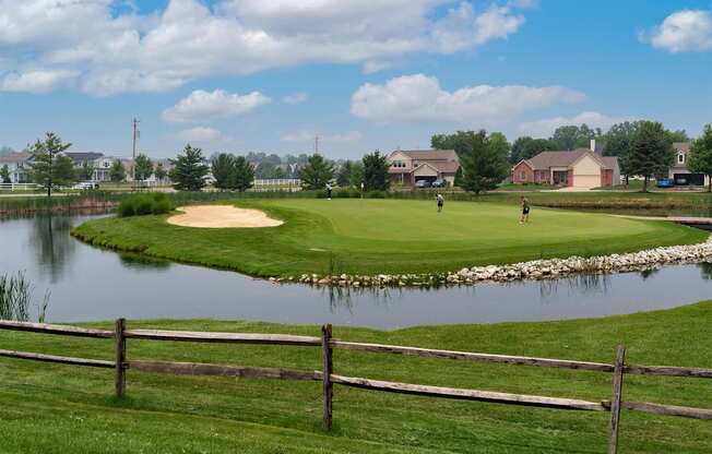 A golf course with a pond and a fence.