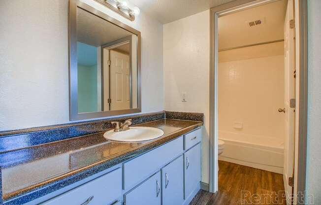 A bathroom with a sink, mirror, and cabinets.