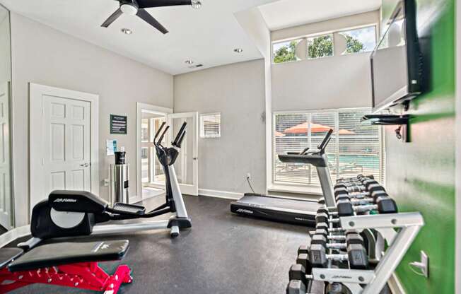 A home gym with a treadmill, elliptical trainer, and dumbbells at Beacon Ridge Apartments, PRG Real Estate Management, Greenville, 29615