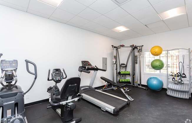 A well-equipped gym with a treadmill, exercise ball, and other fitness equipment.
