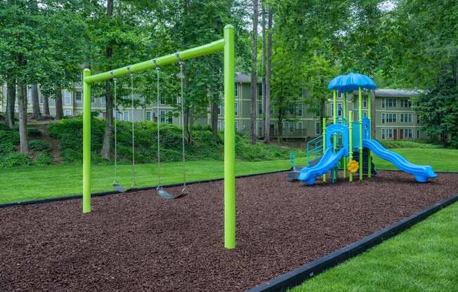 A playground with a blue slide and green swings.