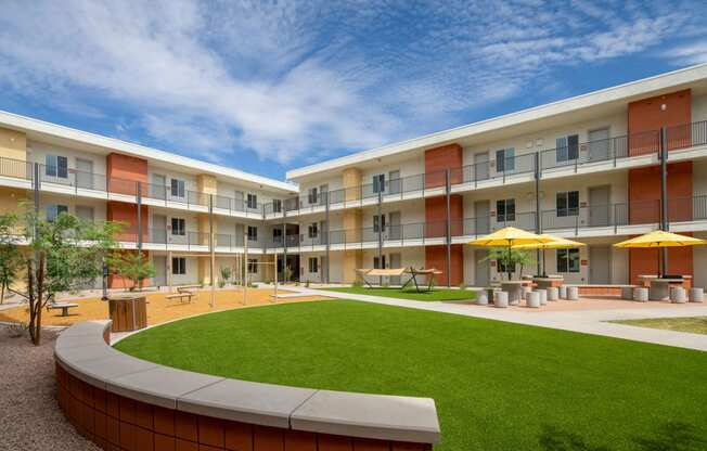 a courtyard with a grassy area and a lawn in front of an apartment building