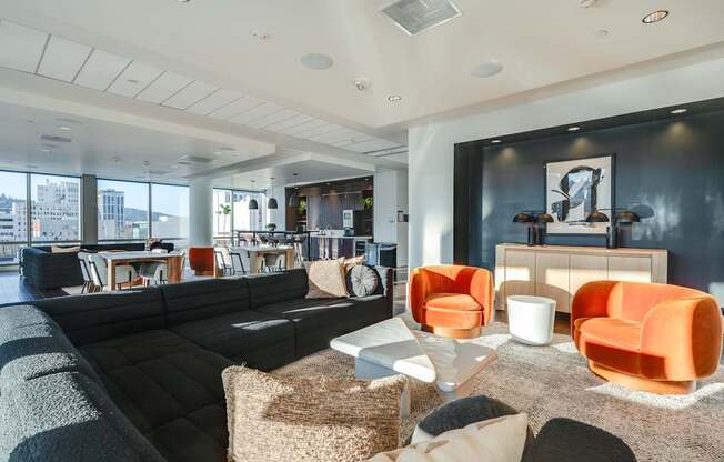 A modern living room with a black couch and orange chairs.