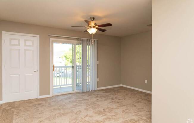 A room with a ceiling fan and sliding glass doors.