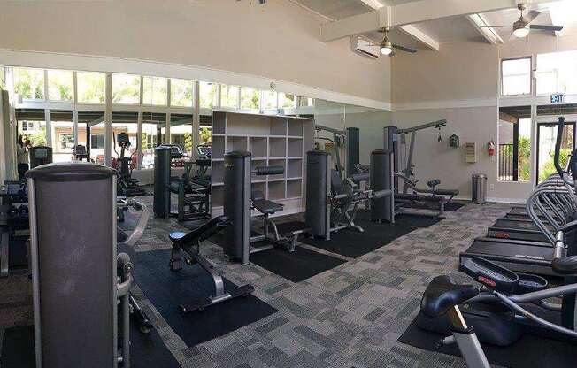 A gym with a variety of equipment including treadmills, weights, and exercise machines.