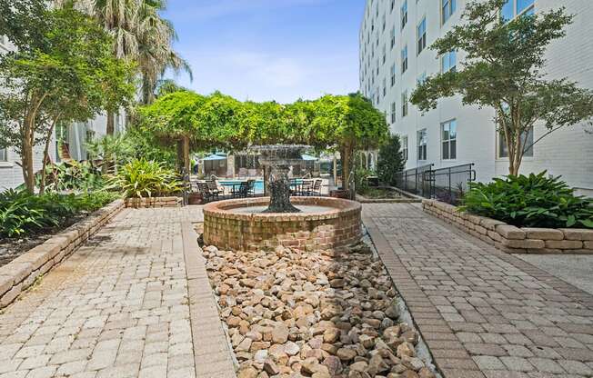 A courtyard with a fountain surrounded by trees and plants.
