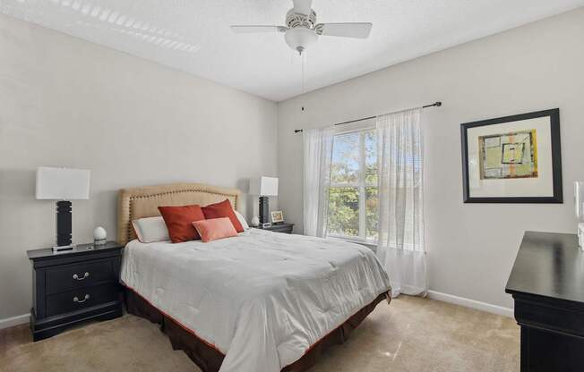 A bedroom with a bed, nightstand, and a ceiling fan.