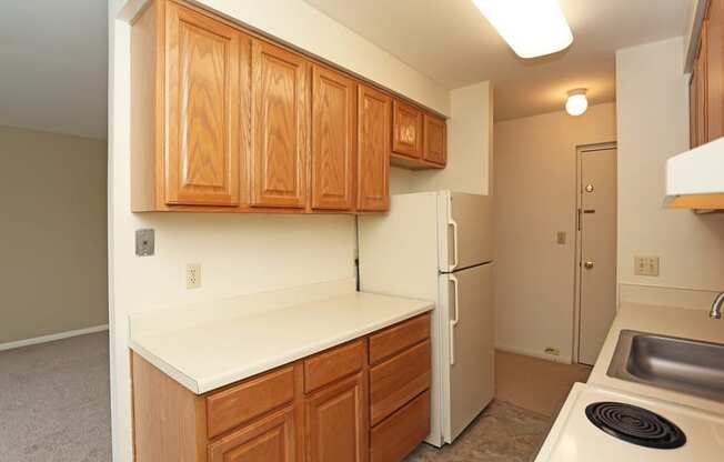 an empty kitchen with wooden cabinets and a white refrigerator