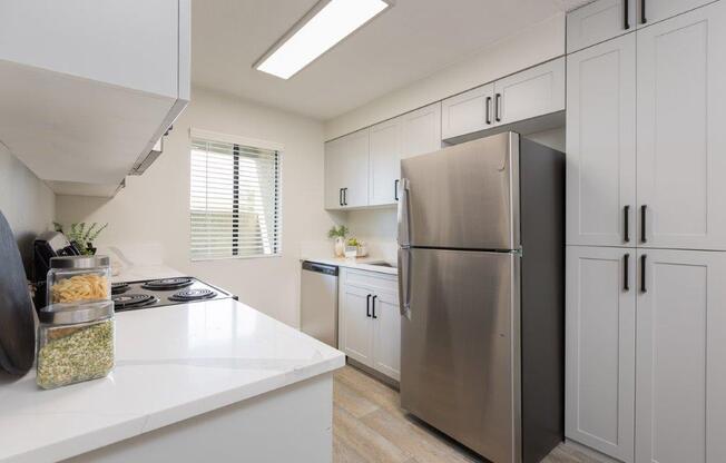 a white kitchen with a stainless steel refrigerator