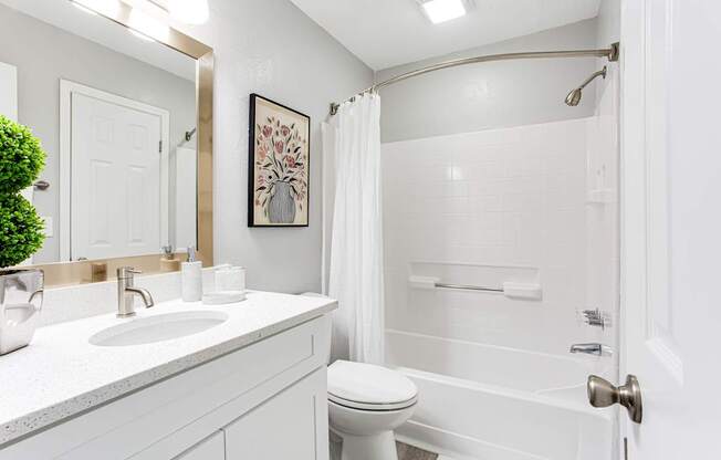 A white bathroom with a toilet, sink, and shower.