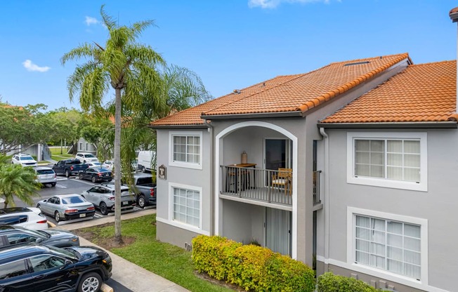 A building with a red tile roof and a balcony with chairs and a table.