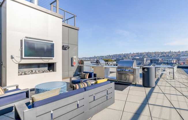a rooftop terrace with a tv and barbecue grill and a view of the city
