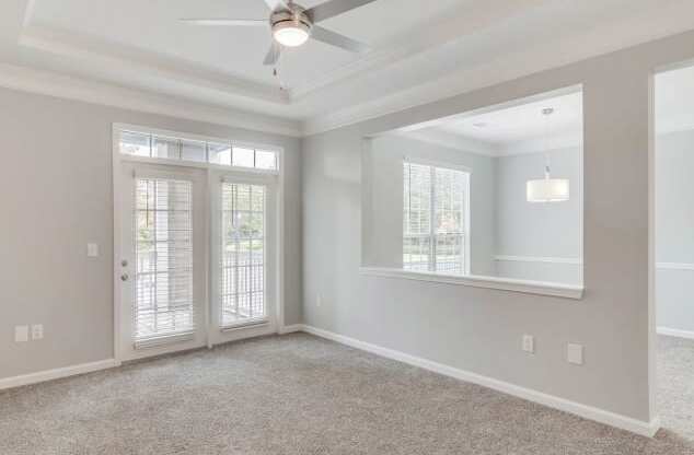 an empty living room with a ceiling fan and a mirror