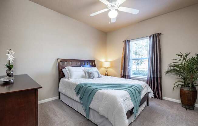 A bedroom with a bed, nightstand, and window.