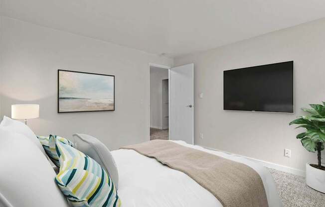 A bedroom with a bed, a painting, a door, and a television.