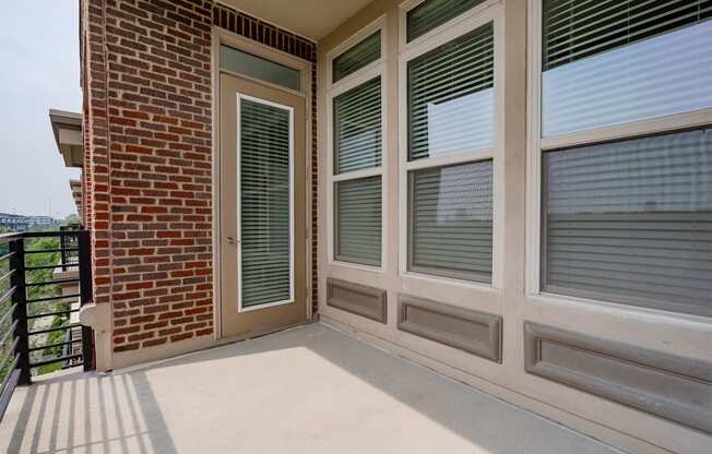 a balcony with a door and a brick wall
